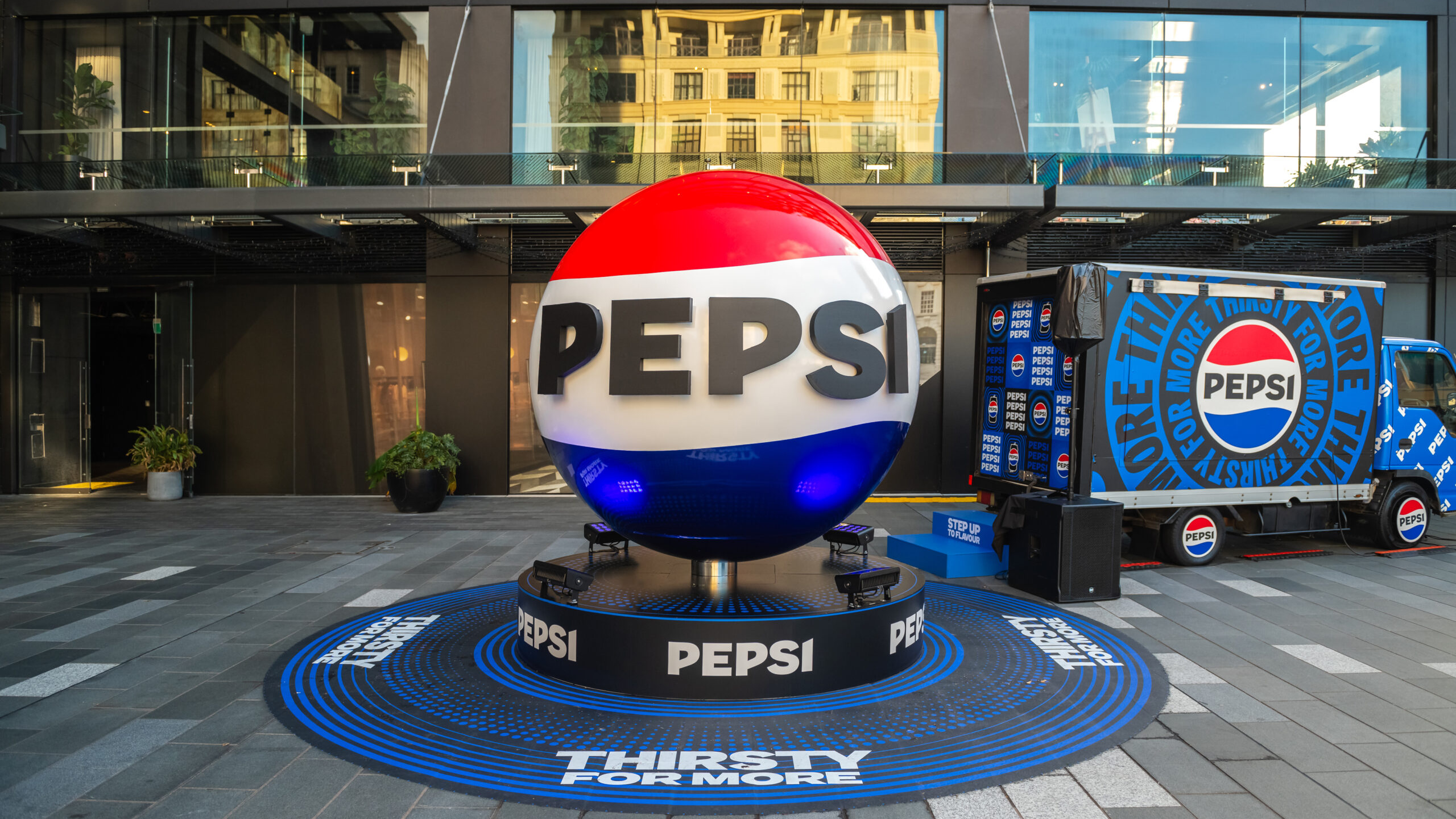 Large 3D Pepsi sphere installation with branded truck and “Thirsty For More” messaging in a public plaza.