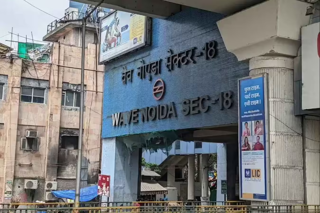 Wave Noida Sector 18 metro station entrance sign with a vertical LIC advertisement beside it