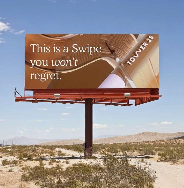 Tower 28 beauty billboard with “This is a swipe you won’t regret” messaging in desert outdoor advertising setting