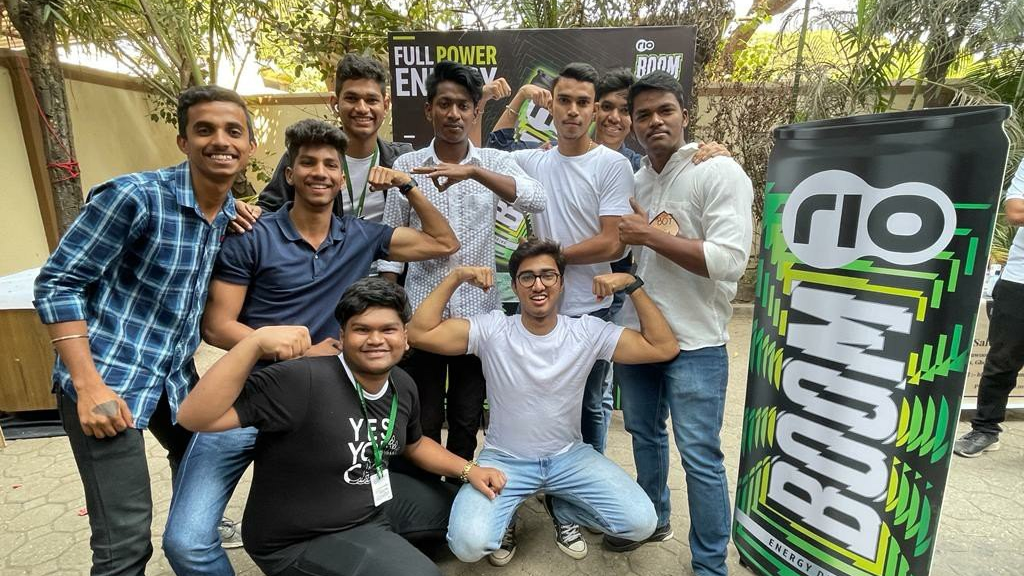 Group of young people posing near a branded energy drink installation during an on-ground promotional activation event.