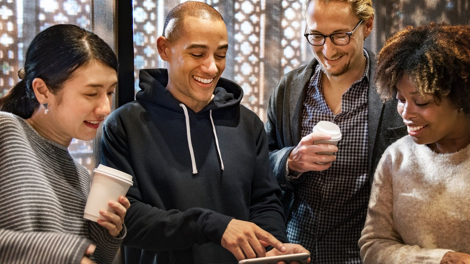 Group of people using a smartphone together representing social commerce, word-of-mouth, and community-driven D2C marketing