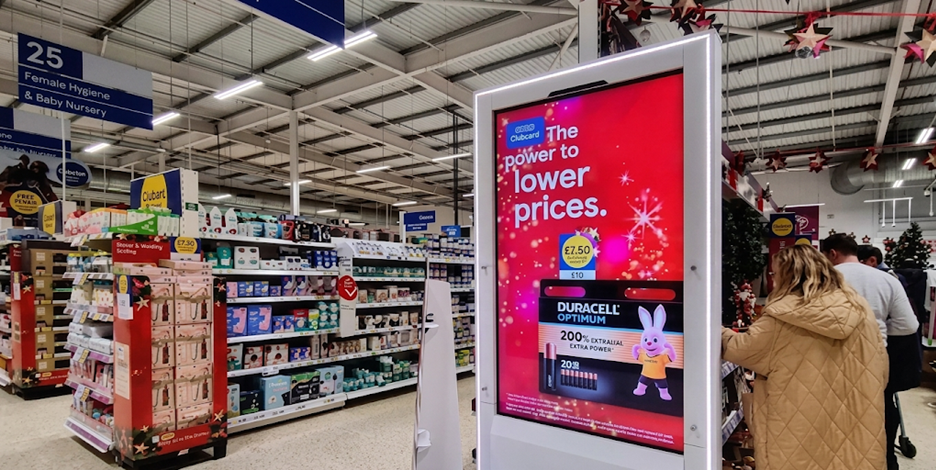 Retail store aisle with digital signage displaying promotional ads highlighting in-store marketing and shopper engagement