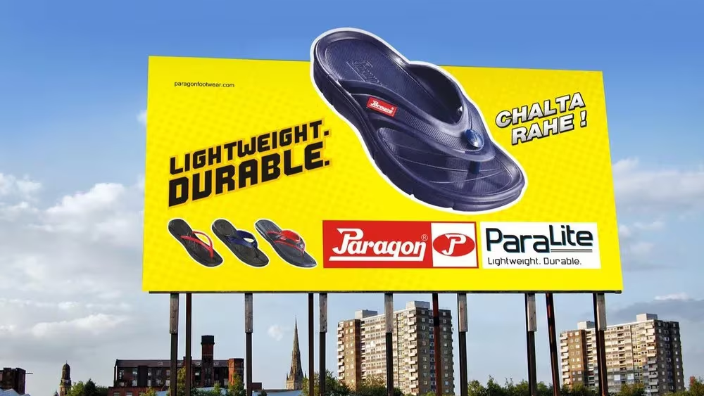 Large roadside billboard promoting Paragon Paralite lightweight durable footwear with a bright yellow background and sandal display.