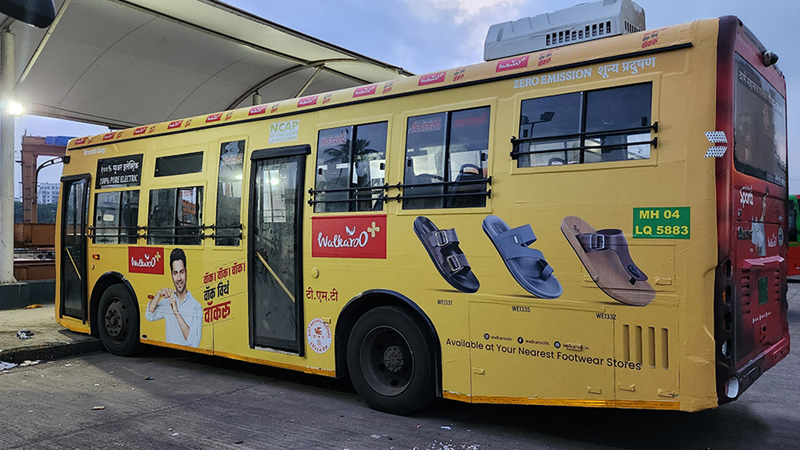 City bus wrapped with Walkaroo footwear advertisement displaying multiple sandal designs and brand messaging.