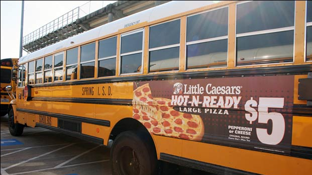 School bus side panel advertisement promoting Little Caesars pizza offer with large pizza visual and pricing