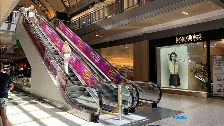 escalator advertising panels in shopping mall targeting high footfall consumer traffic