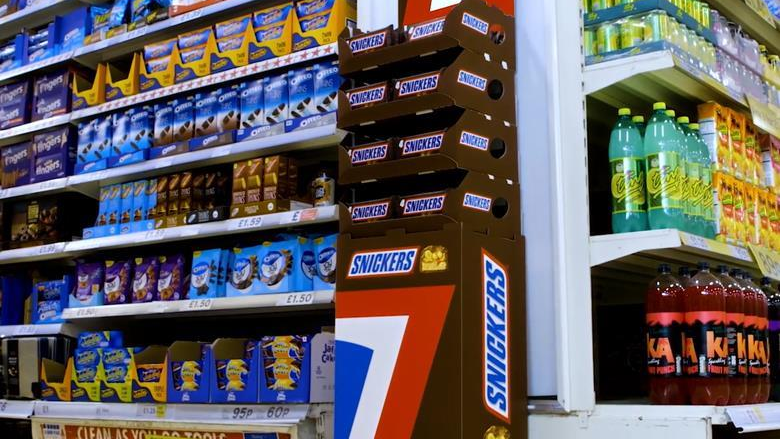 Snickers retail shelf display with branded product stand in supermarket environment