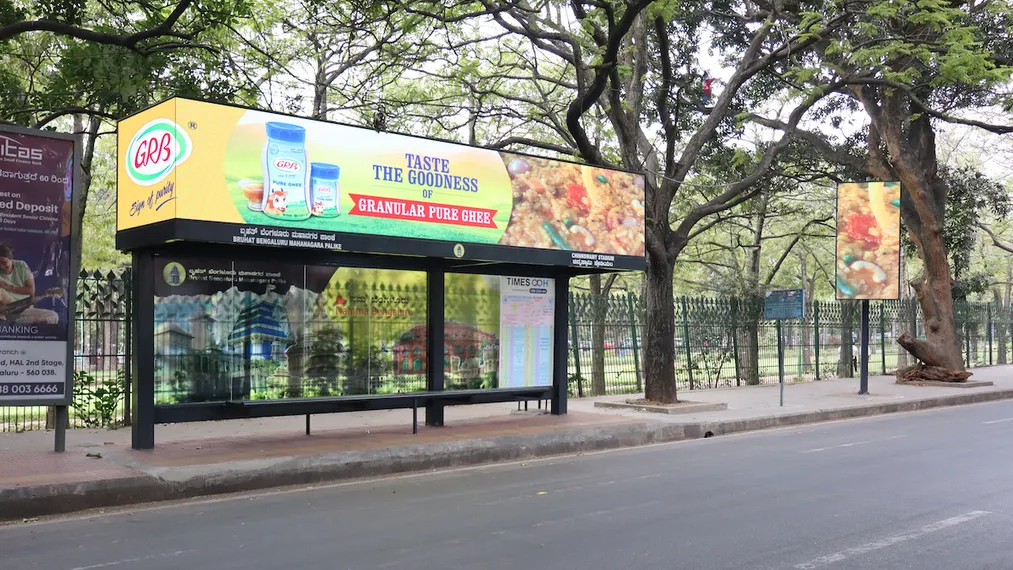 GRB ghee advertisement on bus shelter with illuminated panel in urban outdoor setting