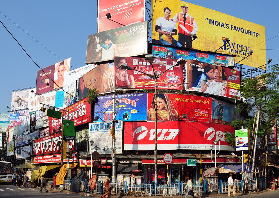 Multiple outdoor billboards and hoardings at a busy urban intersection in India showcasing diverse brand advertisements and high visibility outdoor media