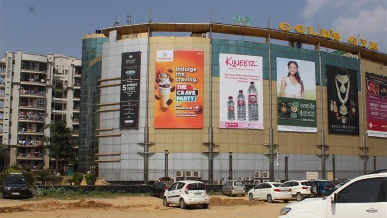 Shopping mall exterior with multiple large format brand advertisements displayed on building facade