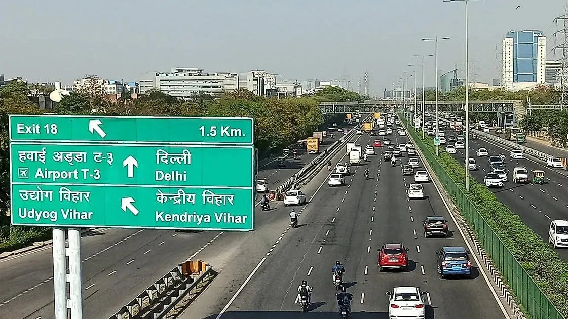 Highway directional signage showing routes to Delhi airport T3 Udyog Vihar and Kendriya Vihar with heavy traffic
