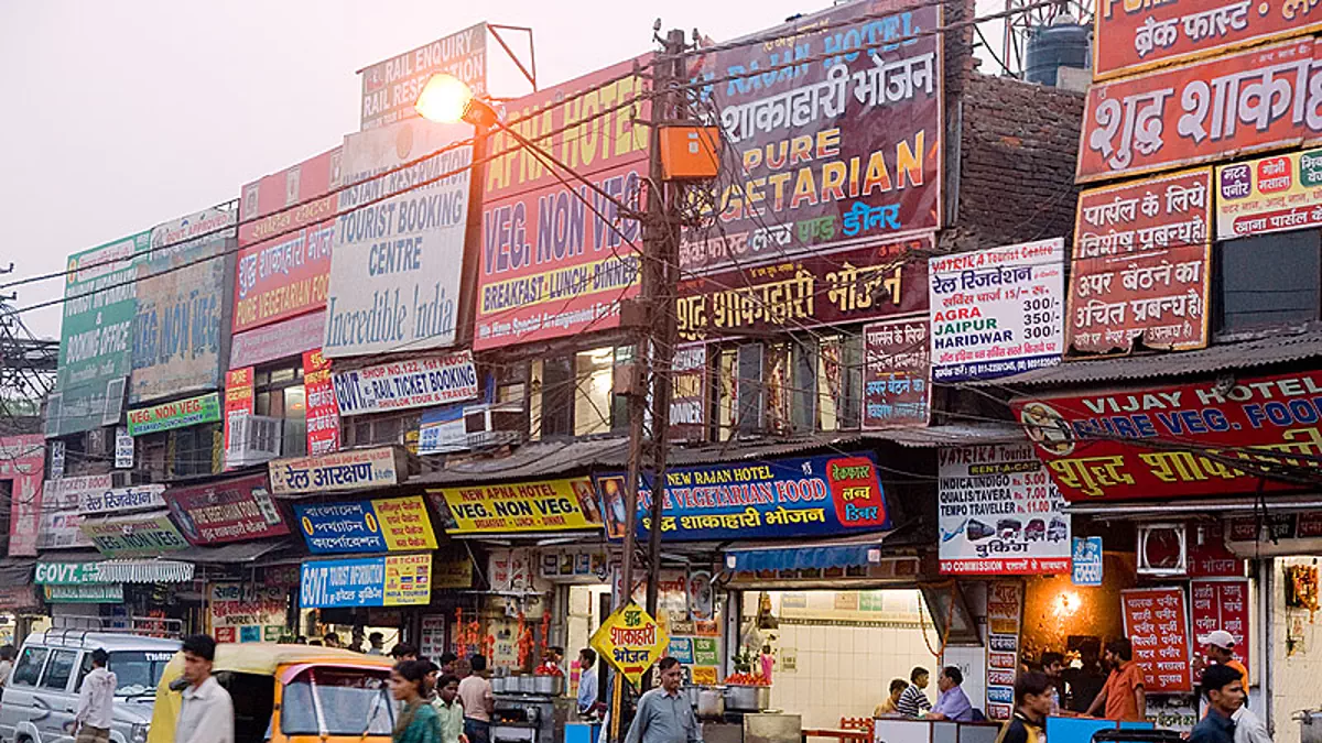 Busy Indian market street filled with multiple shop signboards and hoardings promoting restaurants travel and local services