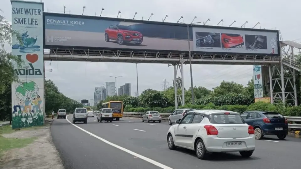 Highway gantry billboard promoting Renault Kiger car with vehicles driving on expressway in urban setting