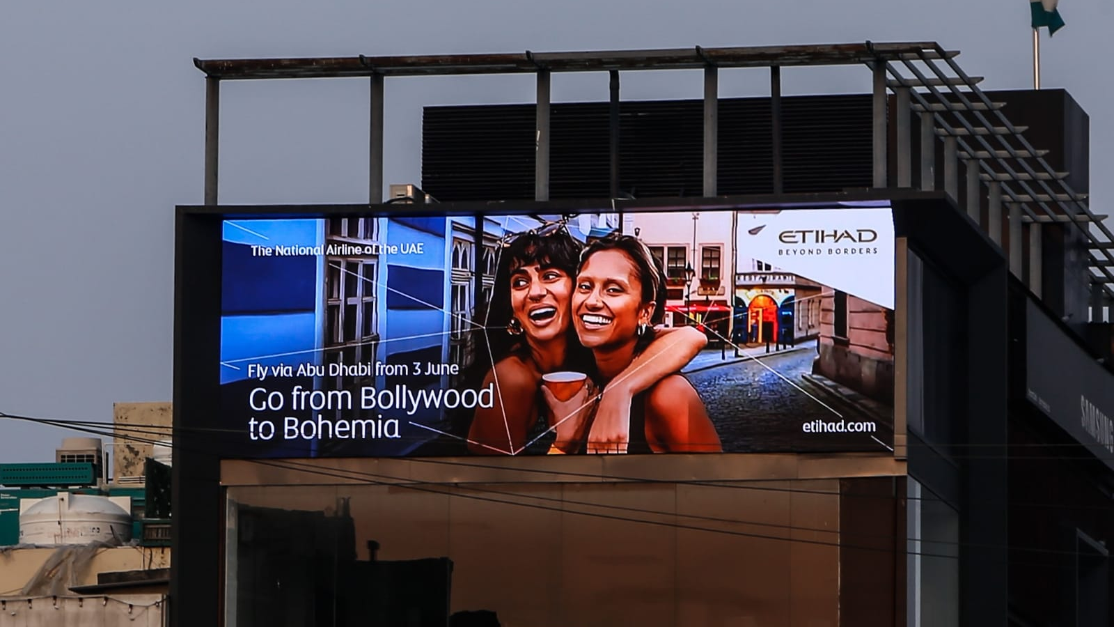 Outdoor LED billboard advertising mounted on urban building displaying travel brand campaign visuals